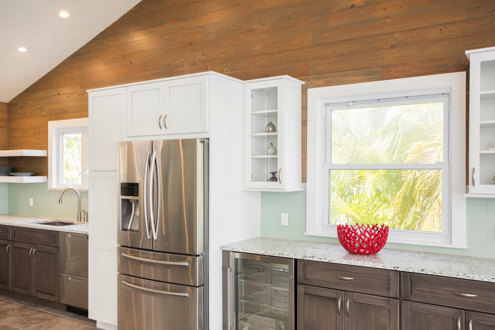 Elegant Key West kitchen renovation with premium white cabinetry, professional stainless steel appliances, and tropical palm views