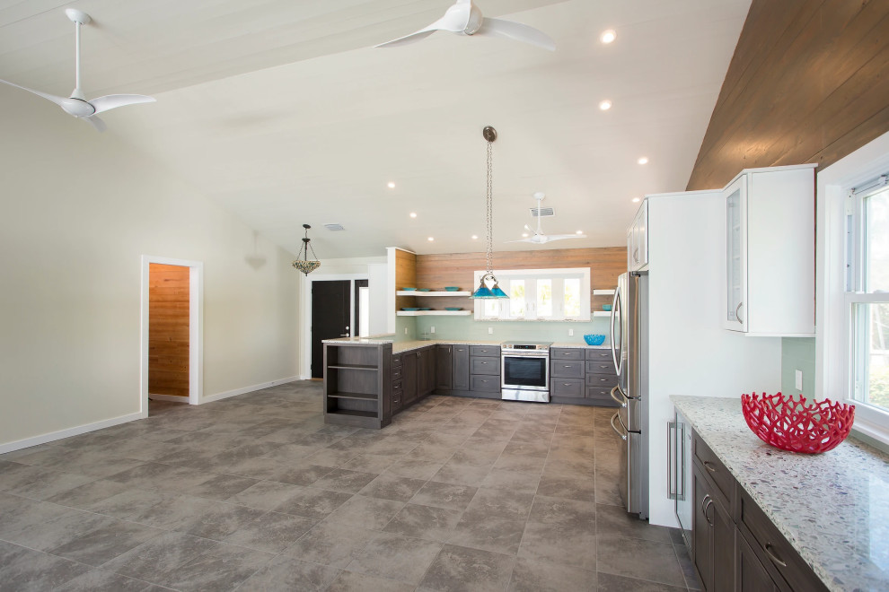 Modern Key West kitchen featuring a custom island with bar seating, designer gray countertops, and premium white cabinetry