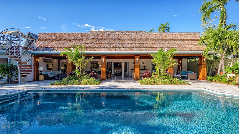 Outdoor swimming pool with tropical landscaping and covered patio in Key West renovation