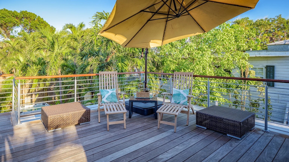 Sunlit wooden deck with yellow umbrella and seating area in Key West renovation