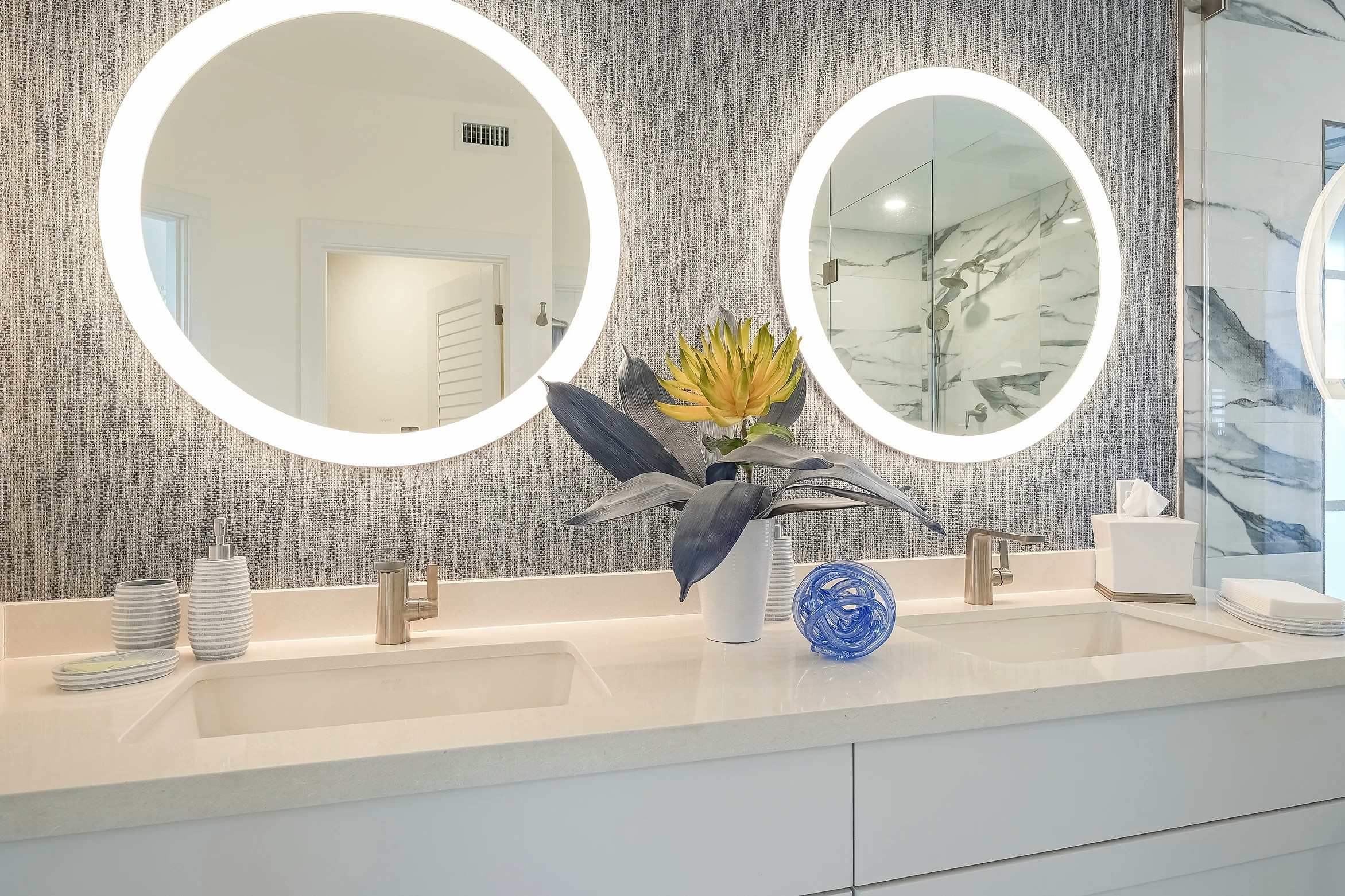 Elegant modern bathroom with round mirror and designer lighting at Sunset Marina by Fogarty Builders