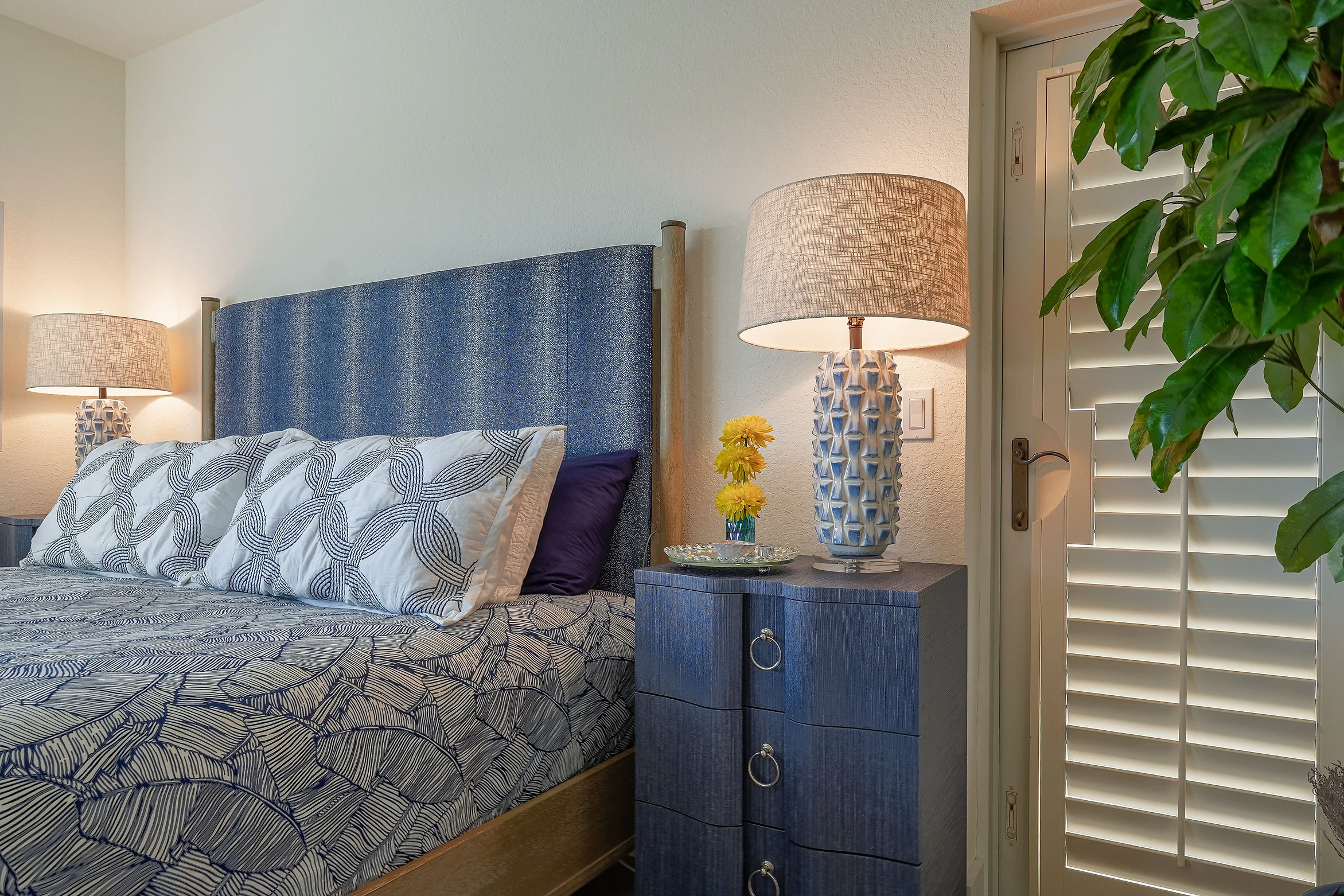 Elegantly designed bedroom with blue headboard and coordinated lighting by Fogarty Builders